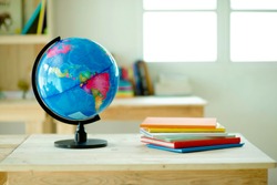Globe on desk.Pinewood table.Shelves with colorful books.Background.Planet Earth and map.Geography lesson.