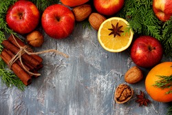 Christmas background - Apples ,orange, cinnamon sticks and walnuts with cypress branches 