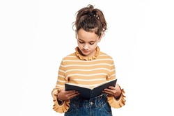 Young girl reading a book while standing on an isolated white background. Literature and education concept.