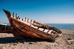 View of an old fishing boat abandoned on the shore at the beach.