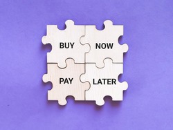 Business and finance concept. Phrase buy now pay later on wooden jigsaw puzzle against purple background.