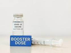COVID-19 VACCINE ampoule with words booster dose and syringe.