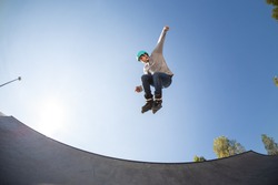 young male inline skater in skate park, in the air doing a jump trick. with protective helmet. rollerblade