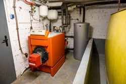 Old oil heating system with oil tank and hot water tank in the basement of a family house - heating with fossil fuels