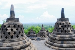 A beautiful woman in an orange dress poses at the Borobudur temple. The biggest temple in the world.