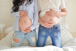  woman’s pregnant tummy, and a man’s beer tummy, a man and a woman hold a tummy