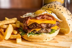 double homemade burger cheddar bacon lettuce and tomato french fries gray background on wood
