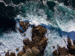 Aerial panorama of waves crashing on rocky coast shore at lighthouse Faro de Cabo Roncudo Costa da Morte Galicia Spain