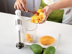 Female Chef Hand Pour Diced Mango to the Juicer Bowl, Process Making Mango Smoothie or Mango Lassi Juice  in the Kitchen