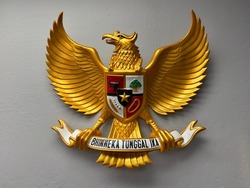 image of a wooden statue of Garuda Pancasila, the Republic of Indonesia's national symbol. The meaning of Bhinneka Tunggal Ika is 