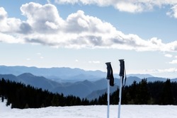 Downhill skiing, winter holidays and mountain resort vacations. Ski poles and background of wide snowy ski slope, silhouettes of mountains and blue sky. Pamporovo ski resort, Rhodopi, Bulgaria