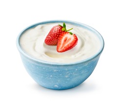 Blue bowl of yogurt with fresh beautiful strawberries isolated on white background. Half and whole strawberry light on fresh yoghurt.