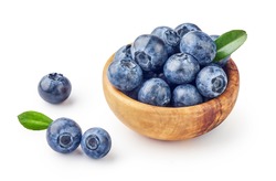 Fresh blueberries with blueberry leaves in wooden bowl isolated on white background.