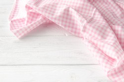Pink cloth on wooden background. Napkin tablecloth on white wood with empty space for text. Top view.