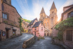 The quaint and charming medieval old town centre of the medieval French village Conques, Aveyron and Abbey Church of Sainte-Foy at sunset or sunrise in Occitanie, France.