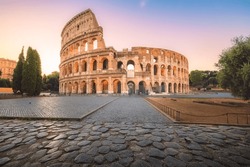 Iconic Flavian Amphitheatre, the ancient Roman Colosseum, a famous tourist landmark, illuminated at sunrise or sunset in historic Rome, Italy.