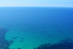 Texture of sea shore with clear turquoise water and sandy bottom. Sea classic blue surface aerial top view. Summer beautiful blurred Background. Selective soft focus.