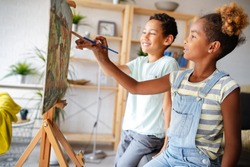 Cute children girl and boy painting together. Education, art, fun and creativity concept.
