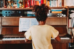 Musical education. Happy black girl playing the piano