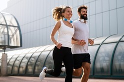 Happy runner couple exercising outside as part of healthy lifestyle. People sport running concept