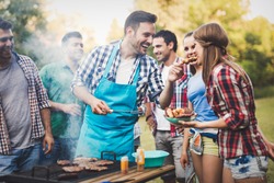 Friends having a barbecue party in nature  while having a blast