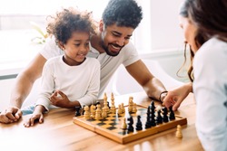 Happy family playing chess together at home