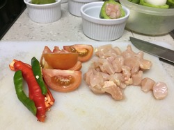 Cross contamination of food, chicken and vegetables such as tomato and chilies are on the same white chopping board