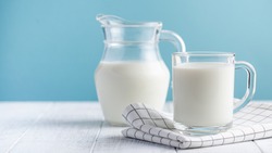  Banner of a glass of milk, a jug of milk on blue background. The concept of farm dairy products, milk day. Copy space.