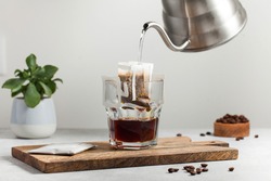 The process of brewing coffee. Water is poured into a drip coffee bag in a mug. Trends in brewing coffee at home.