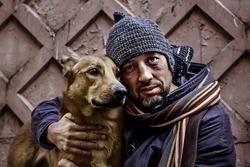 Portrait of dirty tramp hugging his dog. Image with toning and selective focus