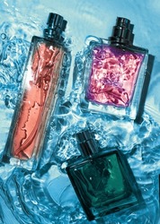 Bottom view on set of spray bottle of perfume stands on a glass table in color of blue.