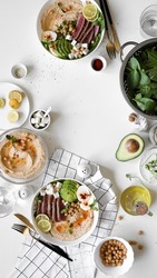 hummus bowl with tuna steak, tofu, avocado, chickpeas, spinach and eggs on plate, ingredients on table, appetizing healthy vegetarian dish, background, top view, close up, flat lay with copy space
