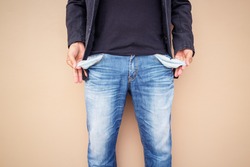 Man showing his empty pockets on cement background.