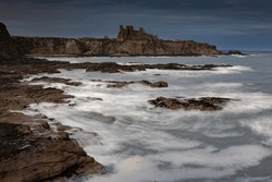 Tantallon Castle in the blue hour, with waves crashing along the shoreline below