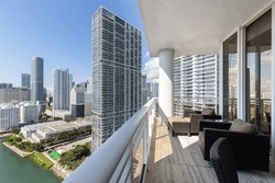 Balcony shot of Brickell Key area, with lots of towers and modern buildings, commercial urban landscape, surrounded by sea and canals, boats sailing, docks, bridges, avenues, blue sky and turquoise se