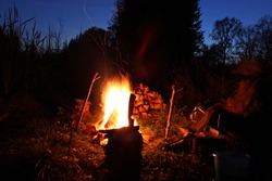 A sparkling campfire at night with some people sitting around