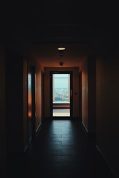 Open door at the end of a dark hallway