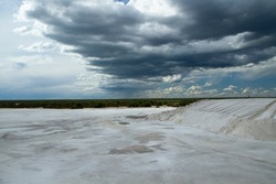 Industrial. View of the natural white salt flats and open cast mining pit under a dramatic sky.	