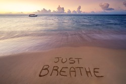 Handwritten Just breathe on sandy beach at sunset,relax and summer concept,Dominican republic beach.