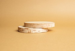 Two wooden discs stacked as a podium on beige background for product presentation. Copy space.