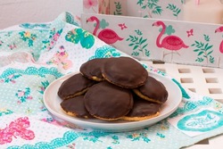 Chocolate and orange cookies on a white plate, decorated in white and blue colors with pink birds, flamingos.