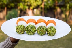 Indian Independence day 15 August, Republic day of India 26 January concepts of tricolour food Three colours of Ladoo or Laddus in hand. orange saffron, coconut white and pista green