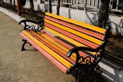 New painted Wooden Park bench. Seating arrangement made at public place garden made of real wood planks and wrought iron metal as arm rest. Garden bench.