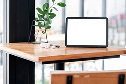 Mockup blank screen tablet and gadget on wooden table.