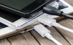 Stack of  Smart Phone Charging with Cable on the Wooden Table.