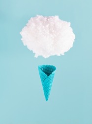 Cotton balls forming a cloud and blue painted ice cream cone against pastel background.  Creative ice cream composition. Summer season, refreshment, dreams, vacation, holidays. 