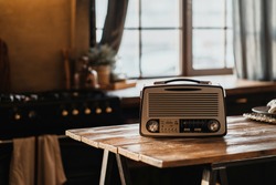 The FM channel is playing music, a stylish retro radio player stands on a wooden table. stylish kitchen in the village, daylight from the window. copy space