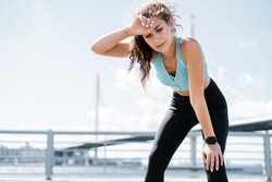 The trainer counts the pulse on a smart watch. Sports and clothing for women. Fitness break in the city. Cardio training for weight loss. The athlete leads a healthy lifestyle.