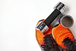 Metallic heavy dumbbell dropped on leg in orange sneaker. Strength training safety precautions