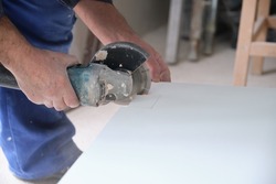 Unrecognizable contractor cutting a white ceramic tile with a radial saw.